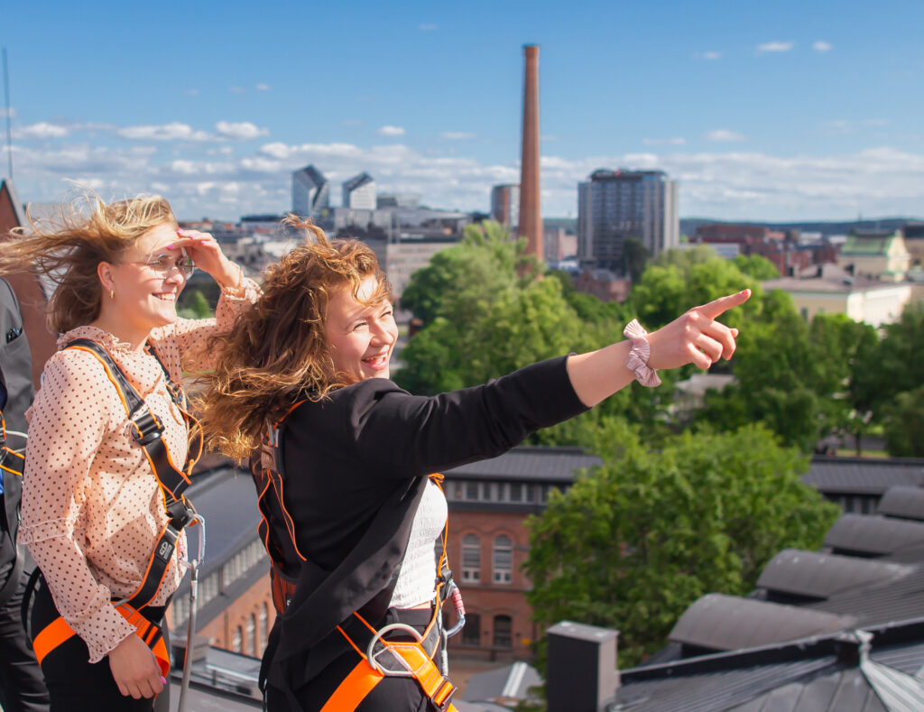Kaksi ihmistä seisoo näköalapaikalla ja katsoo Tampereen keskustan kaupunkimaisemaa.