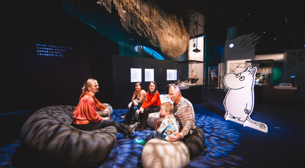 Group of people sitting down on the floor of Moomin museum.
